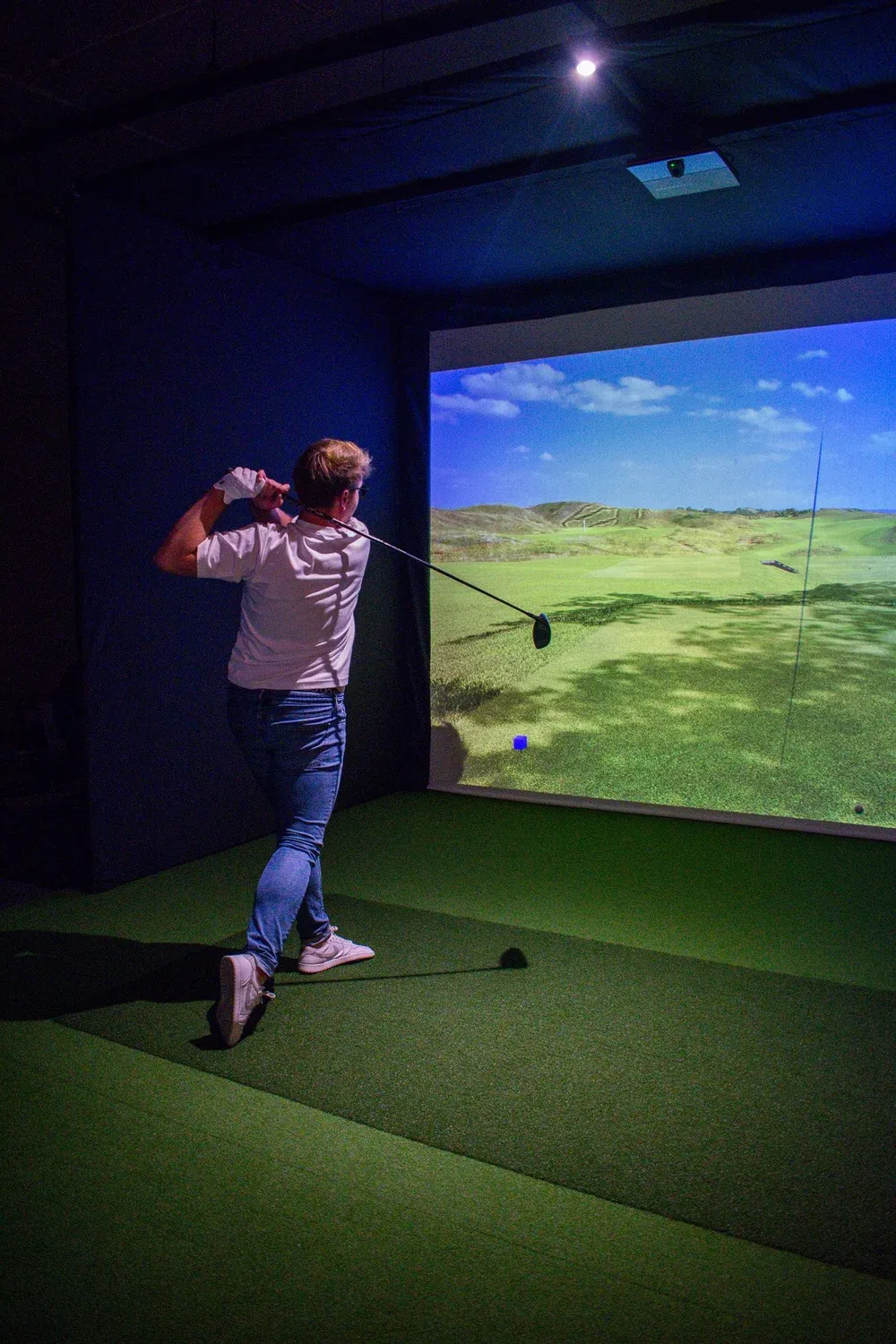 Golfer holding the finish of a swing in a simulator bay